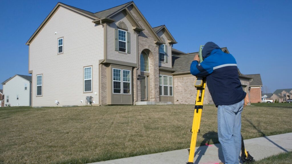 A man using a theodolite to survey the property.