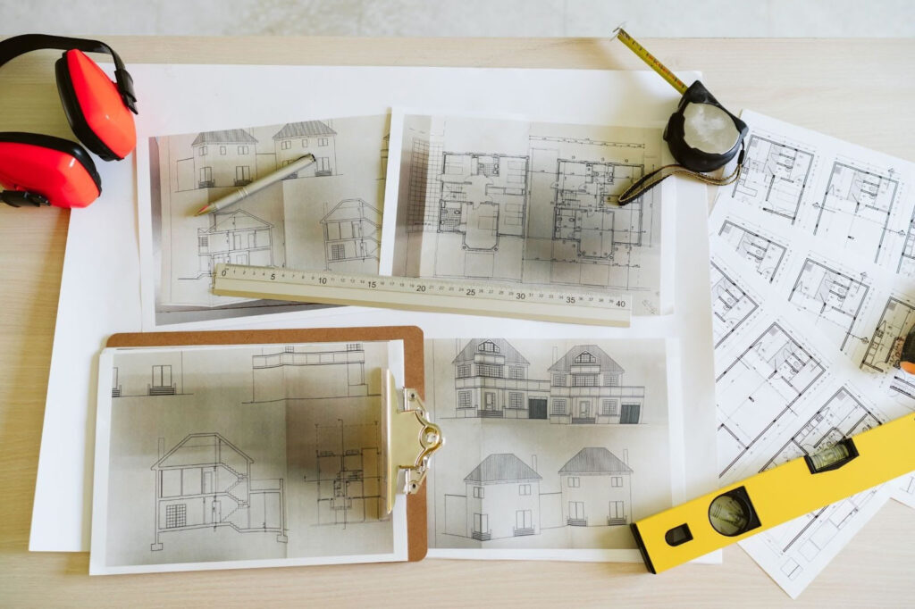 Architectural drawings and measurement tools arranged for planning building elevations and site layout.