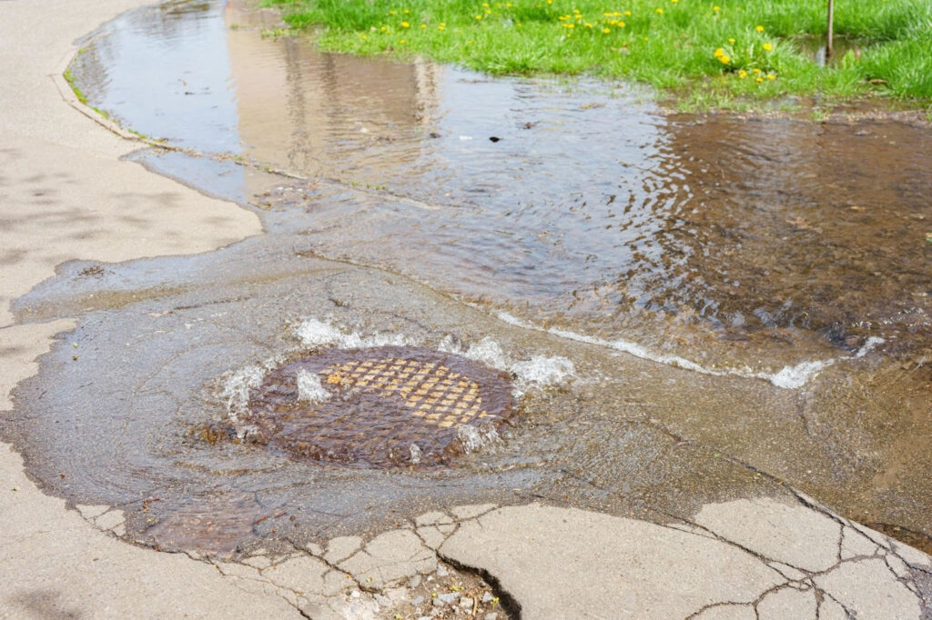 Flooded street with storm drain overflow due to poor drainage system design